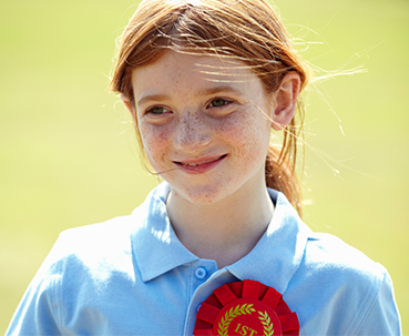 Smiling child wearing winner ribbon